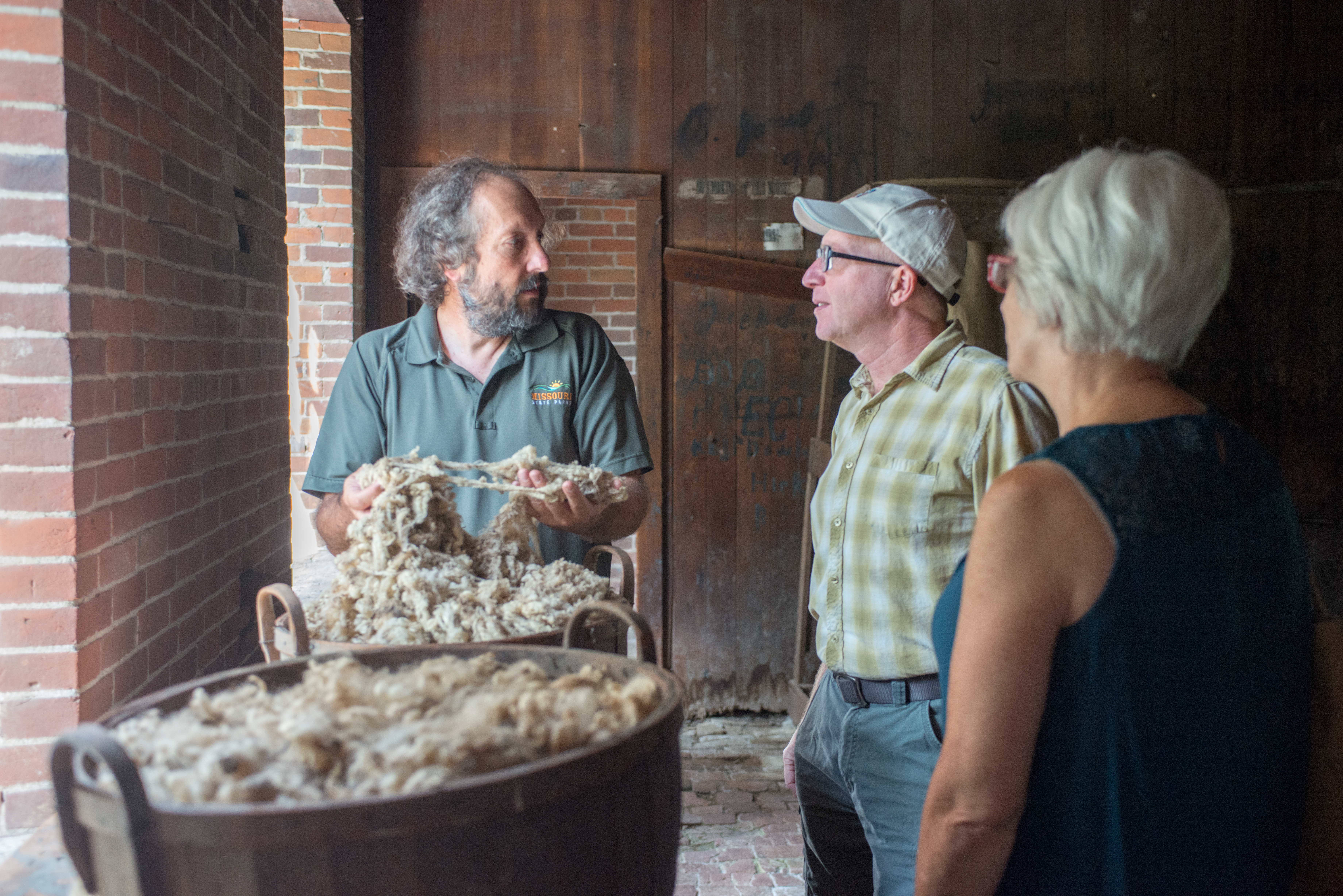 A man showing raw wool to a couple