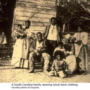 A slave family sitting outside a cabin