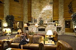 A woman reading a newspaper on a couch in a lodge lobby