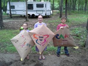 three kids showing off kites they made