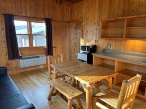Table, mini fridge, microwave, cupboards and window in cabin
