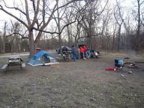 People, a tent and picnic tables in an open area
