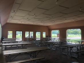 interior of an enclosed shelter with several picnic tables
