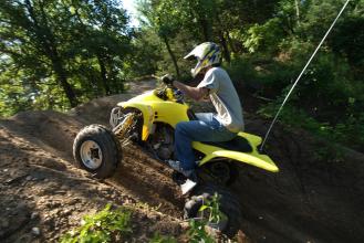 A person on a yellow 4-wheeler driving it up a steep dirt hill
