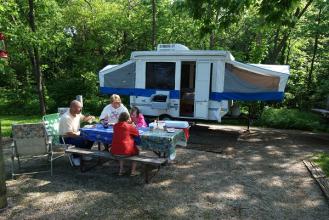 family sitting at picnic table in front of camper