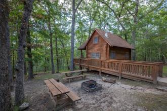 A rustic outpost cabin under shade trees at Lake of the Ozarks State Park.
