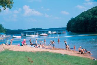 People playing and swimming at a beach on a lake.