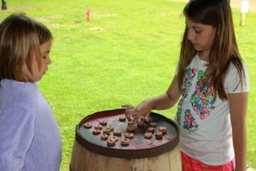 two girls playing checkers on top of a barrel