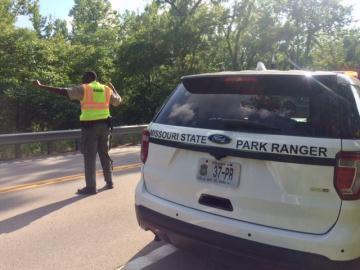 Ranger directing traffic with car in background
