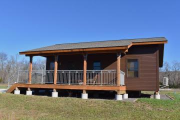 Front view of cabin with brown siding and covered front porch.
