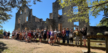 Students stand in front of the ruins of a stone building