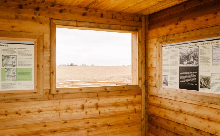 Inside of a wooden cabin with an information board about the Battle of Island Mound