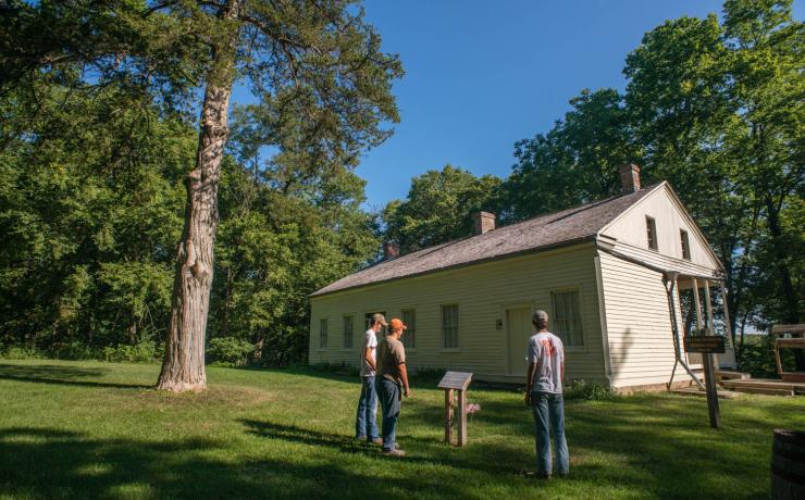 3 people looking at a historic building with a plaque out front