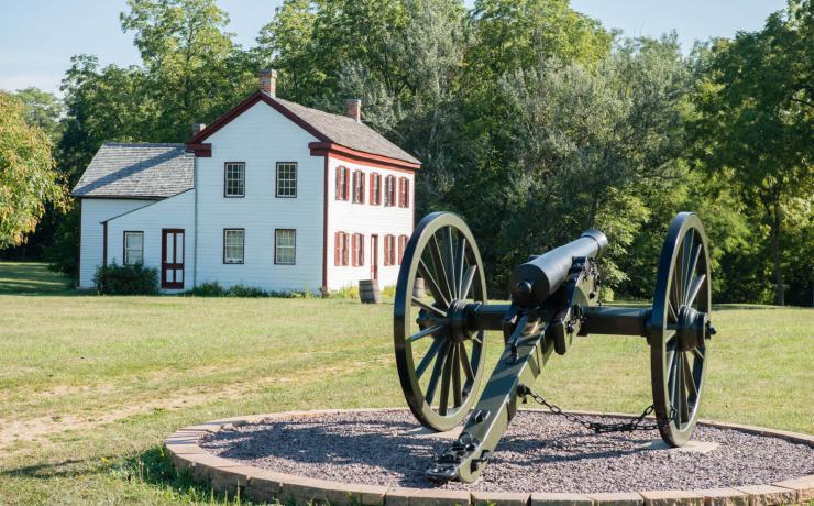 A civil war cannon with a white house behind it