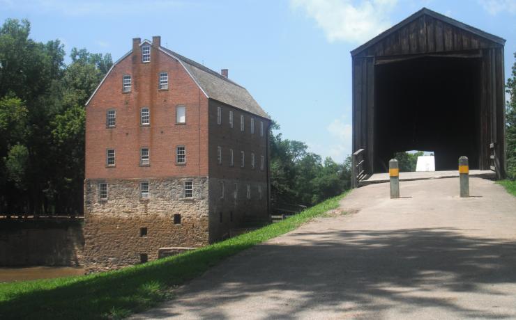 View of an old mill brom a near by walking path with a covered bridge