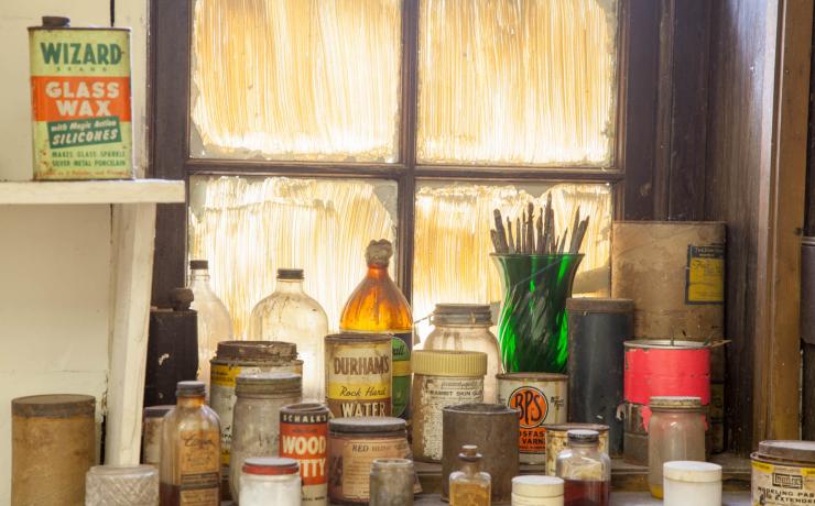 Jars of paints and mason jars sitting by a tinted window