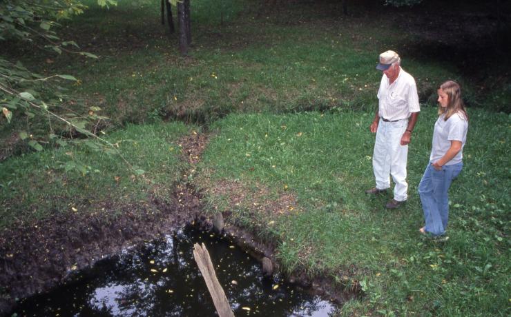 Two people looking at a small pond