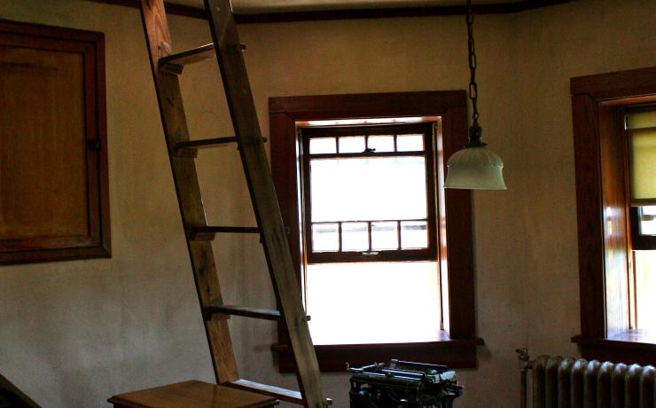 An office with a ladder leading up to an attic