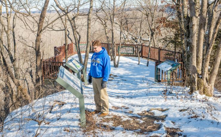 A person reading an informational sign on a snow-covered path
