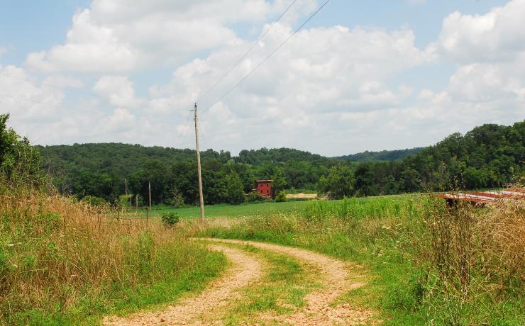 A dirt road with a red mill in the background