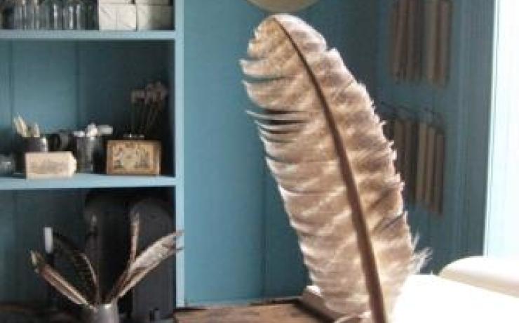 A close-up of an ink and quill sitting on a wooden desk
