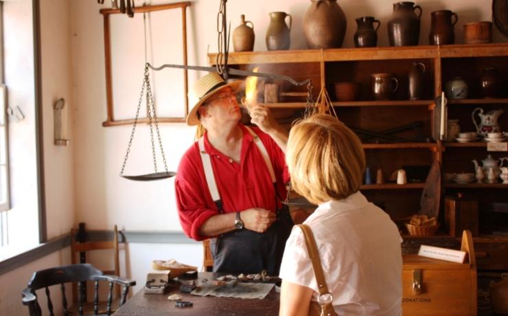 A historical re-enactor showing general store goods to a visitor
