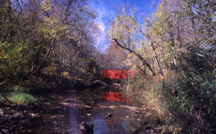 A red covered bridge over a creak