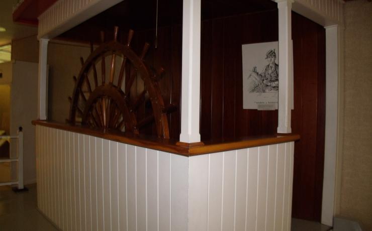 A room with a ship's steering wheel on display