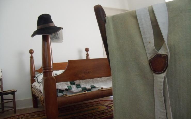 A wooden bed, a hat on the foot rest