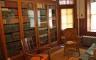 A home library with many books on shelves with glass doors and two chairs in front of them