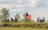 People setting off two cannons next to the American Flag