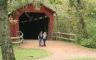 Two people standing in front of a red covered bridge