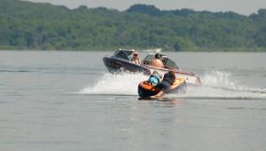 Two kids riding in an inflatable boat tied to a power boat