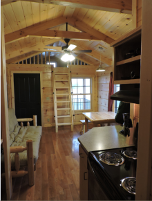 Interior of cabin showing stove, futon, table and loft.