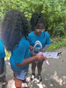 Two children work on a nature scavenger hunt outside