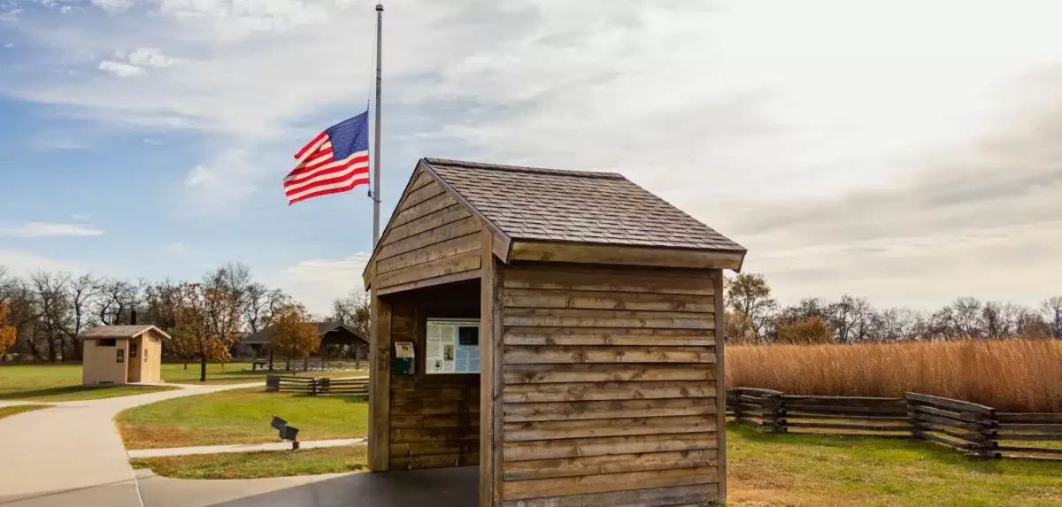 Covered interpretive kiosk with American flag at half staff