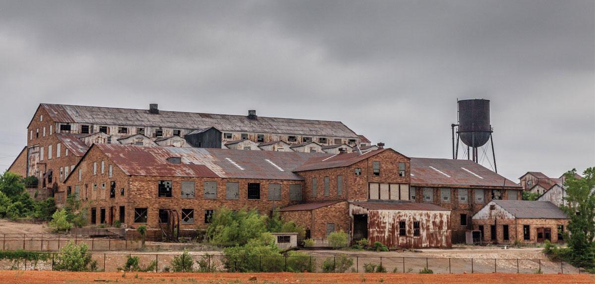 Complex of old, rusty buildings under overcast sky