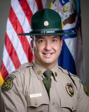 Ranger Lucas Anderson standing in-front of flag