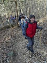 A line of people hikes up a hill in the woods