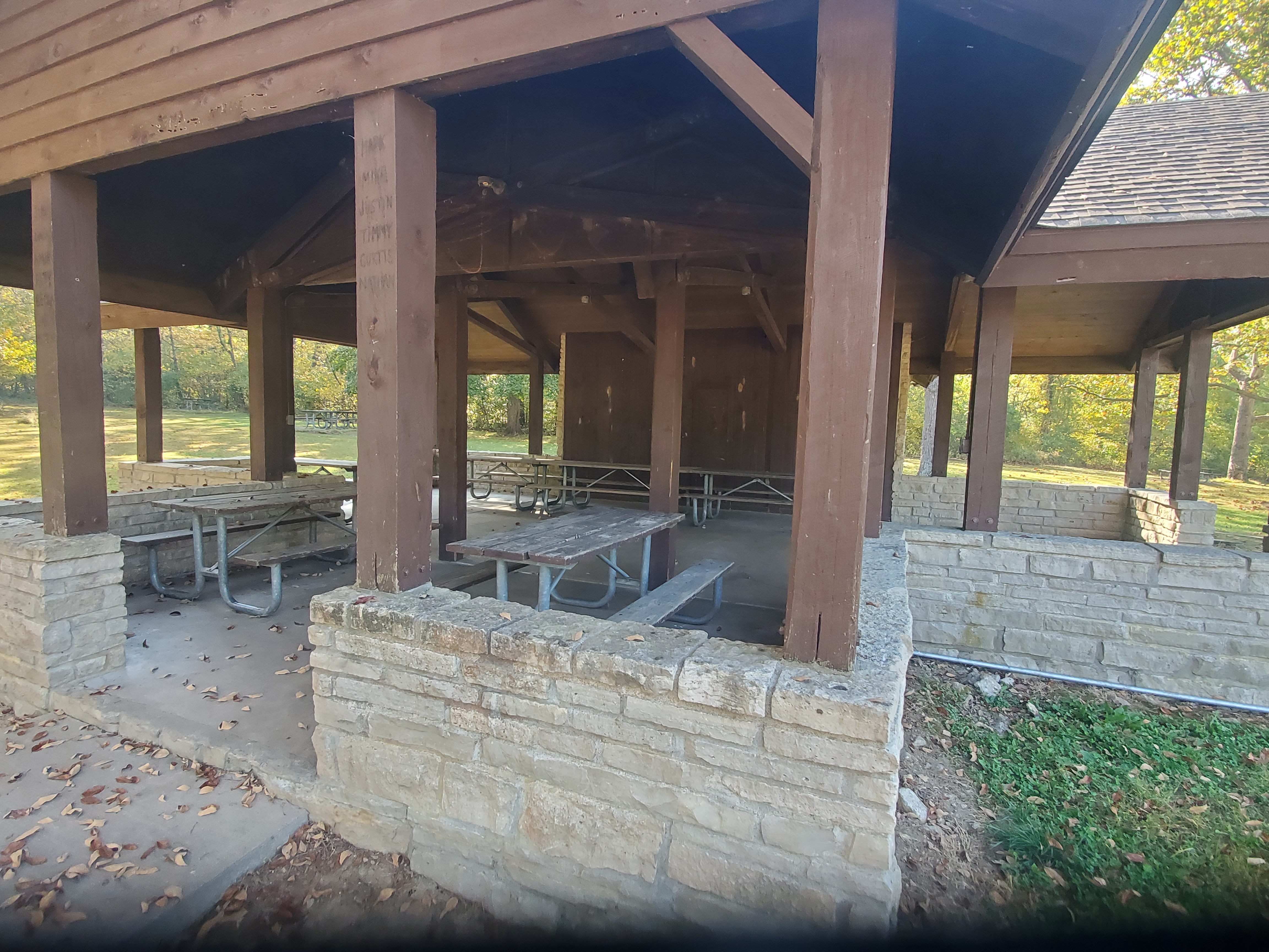 Picnic tables inside the wood-framed open shelter