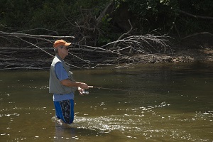 a man standing in the creek fishing