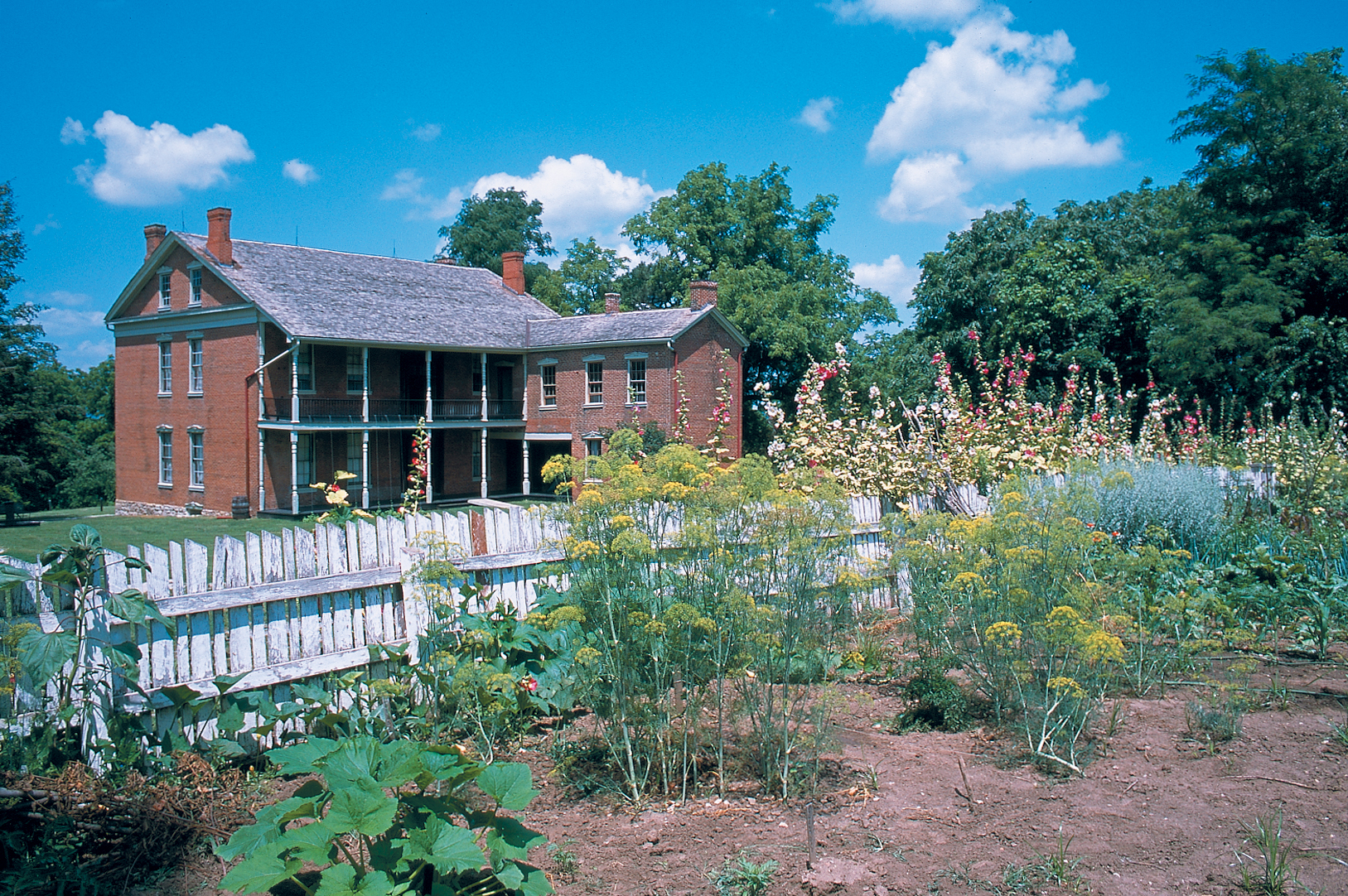 Exterior of the two-story, red brick Anderson House with the gardens in the foreground