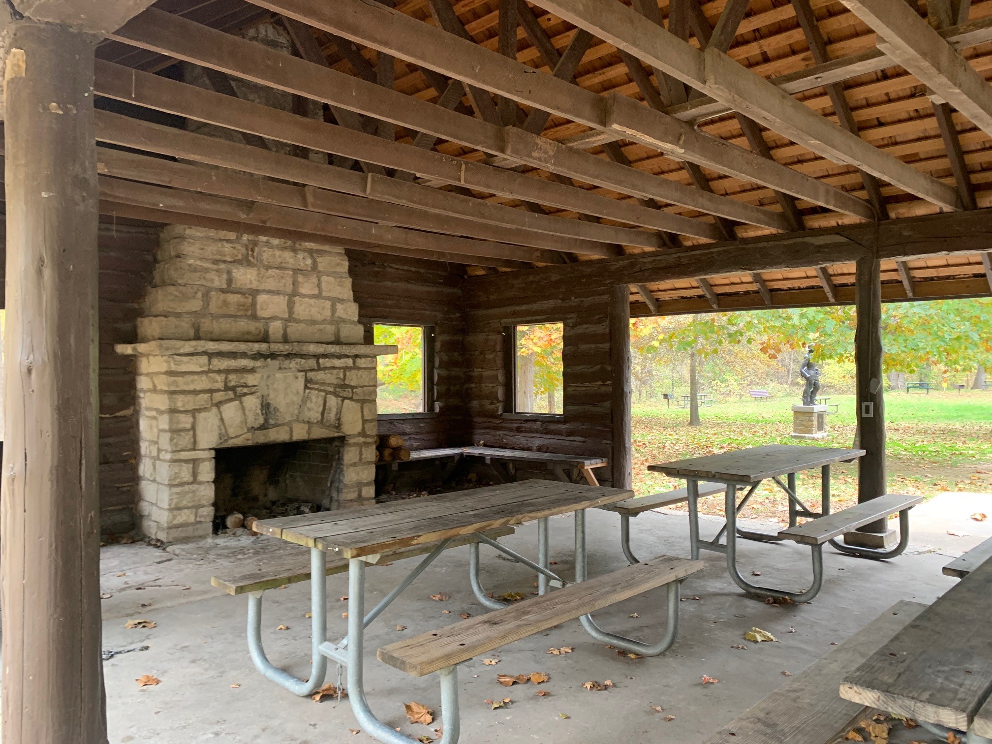 Wooden picnic tables and stone fireplace inside the open shelter