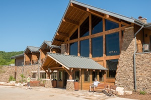 exterior of lodge with lots of windows, rock and wood 
