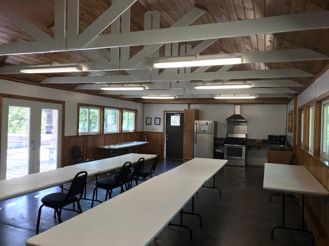 Tables, chairs and kitchen area inside the enclosed shelter