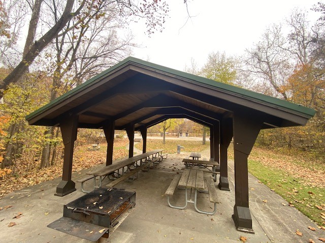 View of the shelter, picnic tables, a grill and the water fountain in fall