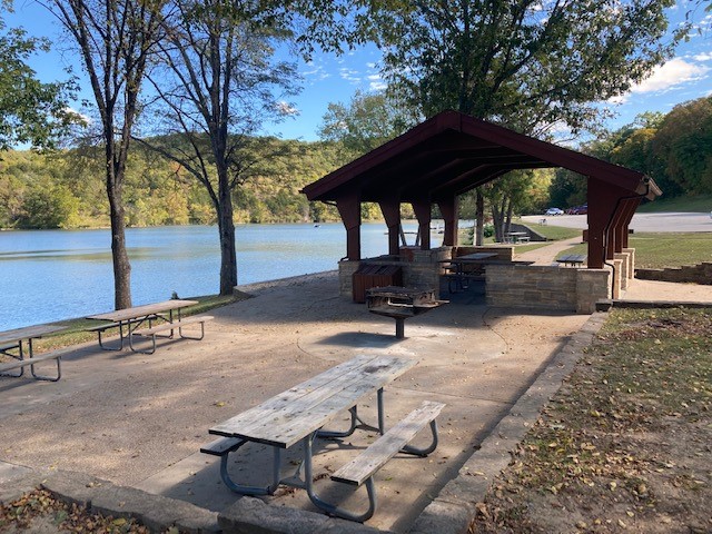Picnic tables, grill and open shelter next to the lake