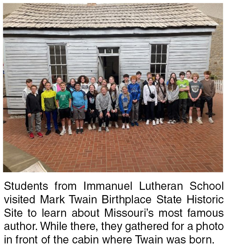 Group of school age children posing in front of historic cabin of Samuel Clemens