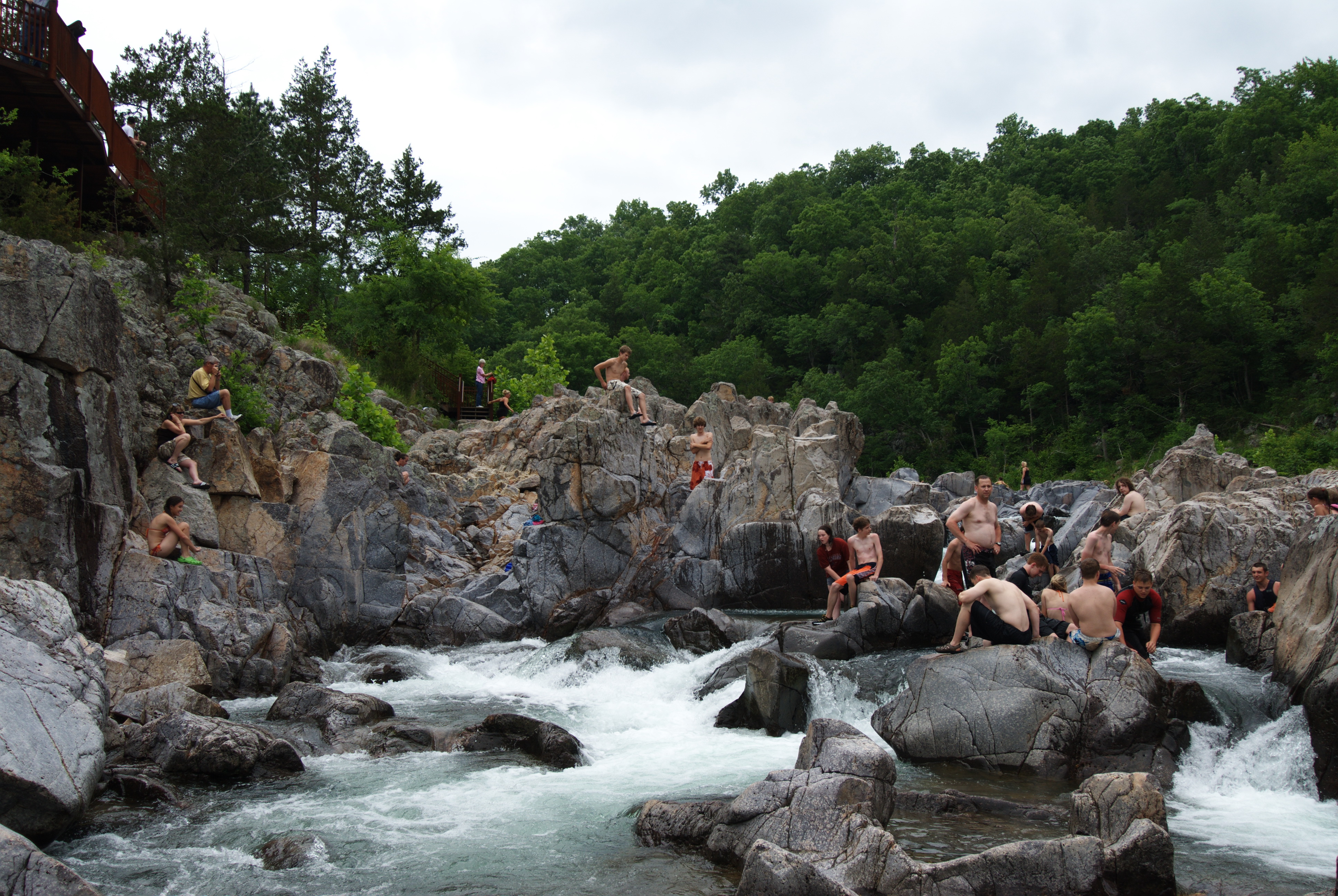 people sitting on the rocks and swimming in the water