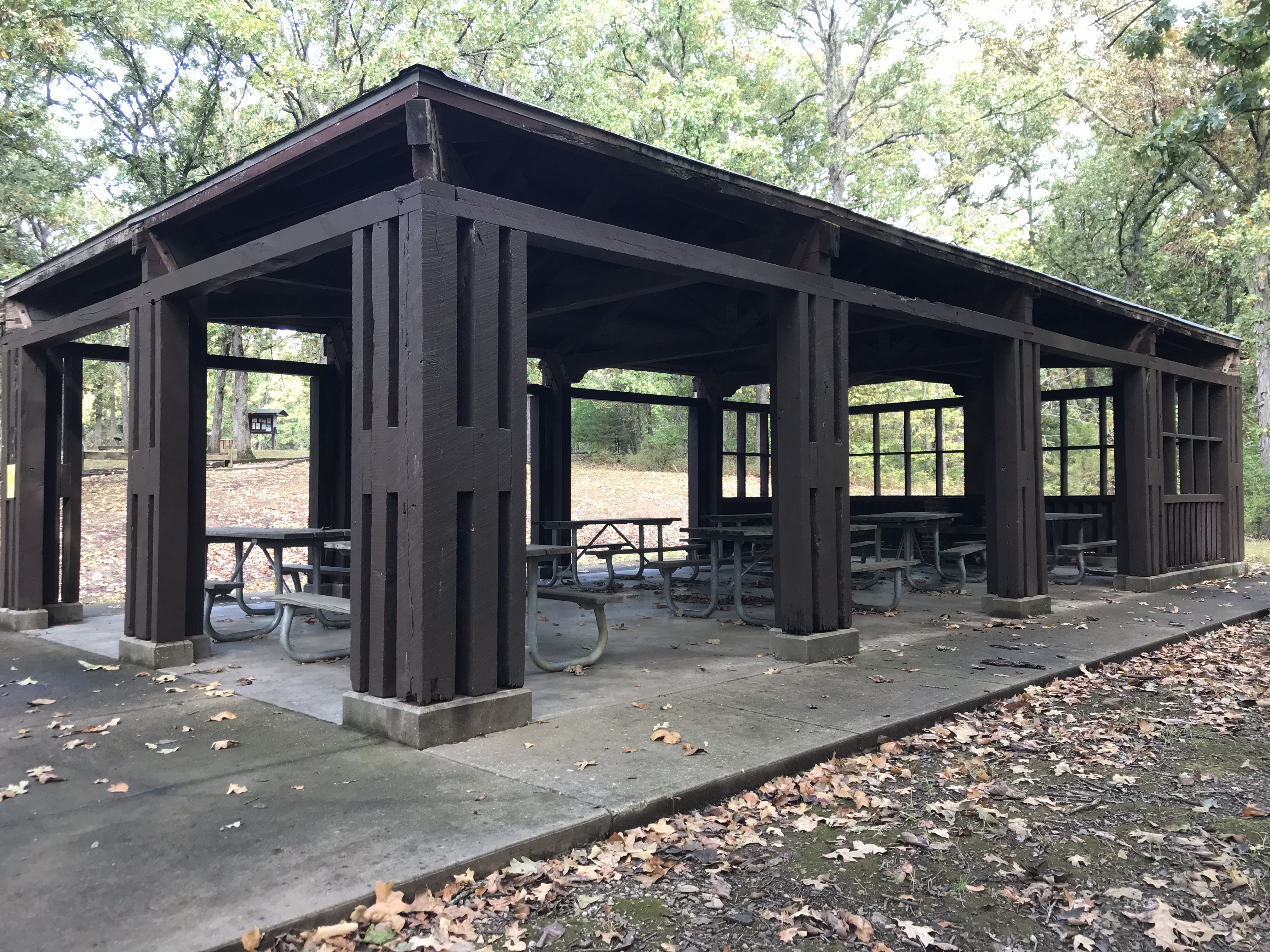 A closeup view of the shelter's wooden pillars and the picnic tables under the roof